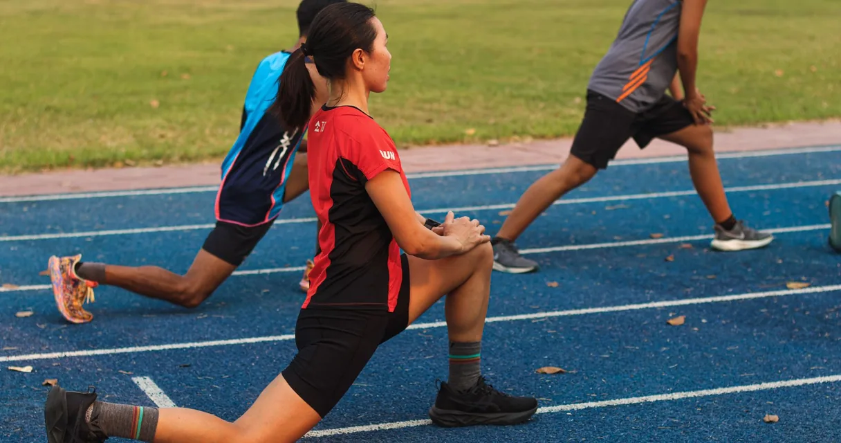 Atletas alongando na pista de atletismo antes do treino